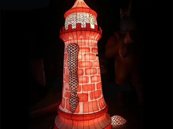 Faro luminoso LED de fábrica de ladrillo en franjas rojas y blancas, con la linterna acristalada iluminada en la parte alta