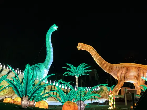 Escena de saurópodos luminosos con palmeras y helechos iluminados