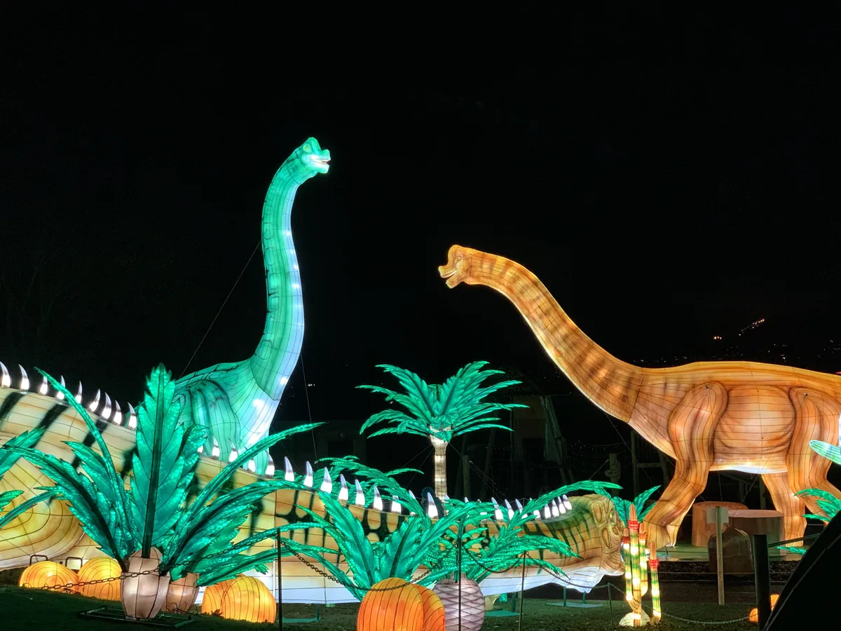 Escena de saurópodos luminosos con palmeras y helechos iluminados