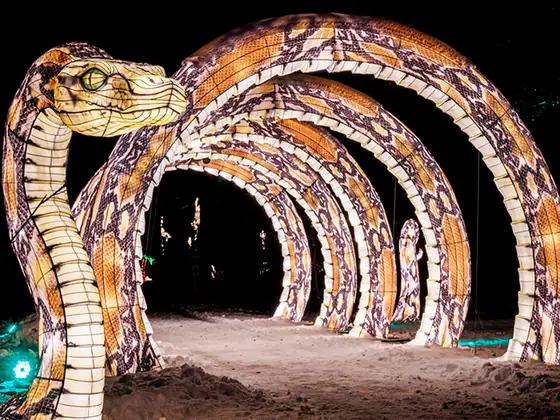 Túnel de arcos luminosos rematado por una cabeza de serpiente