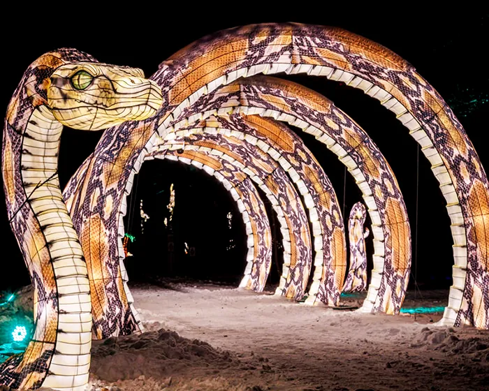 Túnel de arcos luminosos rematado por una cabeza de serpiente