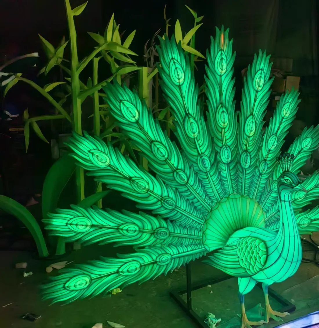 Pavo real luminoso de gran formato con la cola desplegada, iluminado por dentro en verde