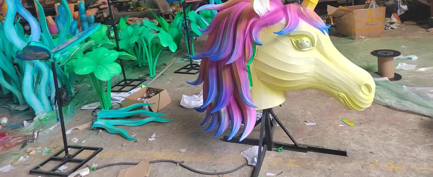 Cabeza de unicornio de gran formato en seda tensada, junto a flores y mariposas luminosas